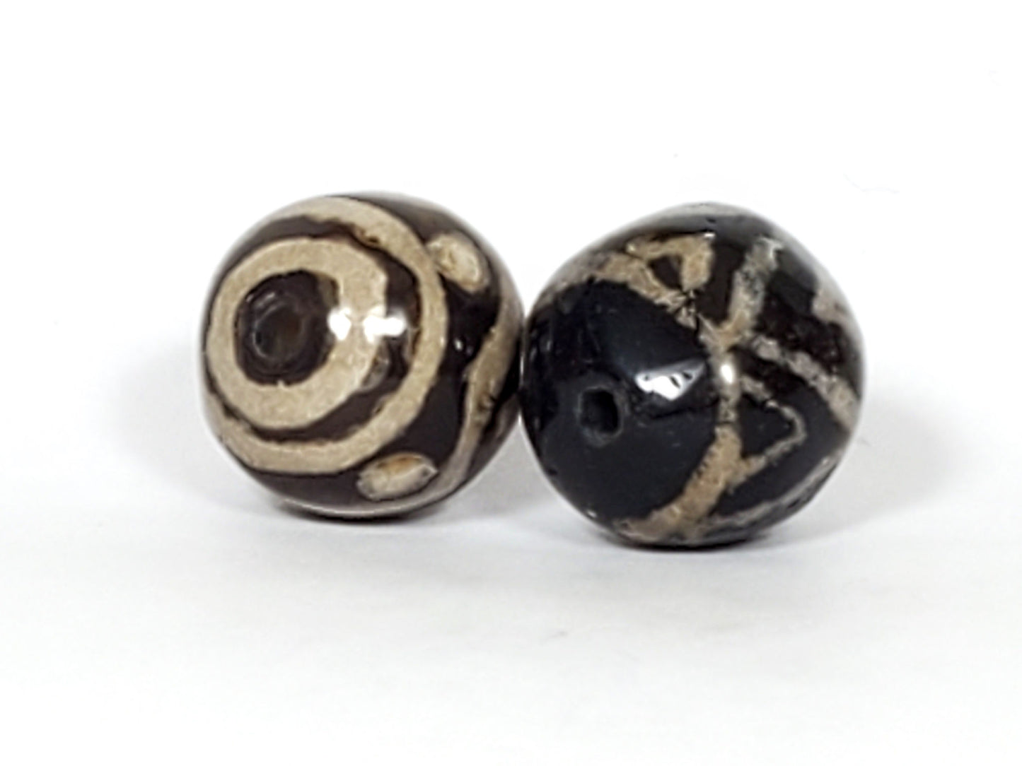 V-FA-062526-TSWS-TT pair vintage faux-antique round dzi, close angle, black ground sandy-cream motifs, unretouched