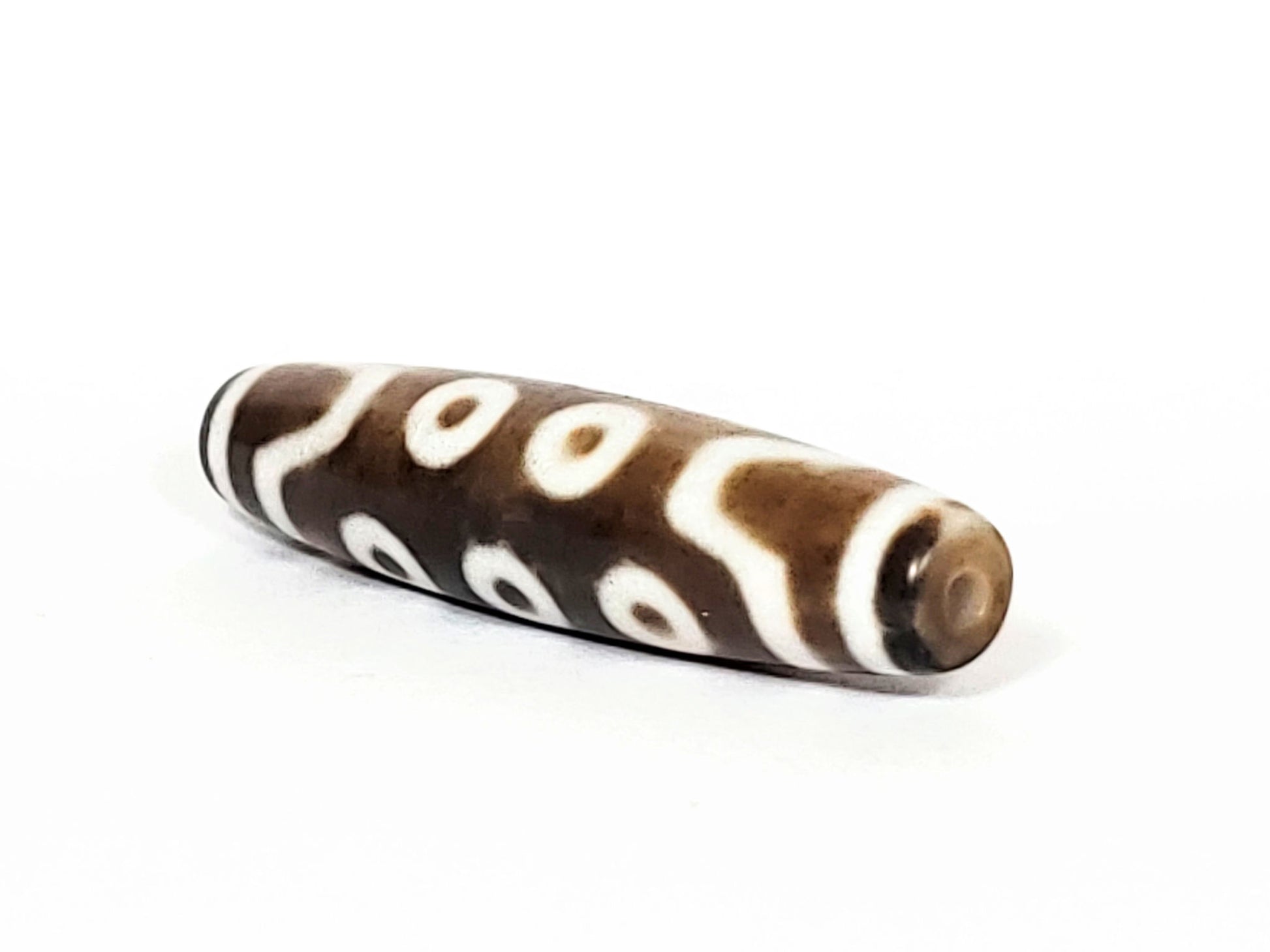 N-062426-10E new ten eye dzi 58.5x13.4mm angled view showing asymmetric taper narrower drill hole end unretouched