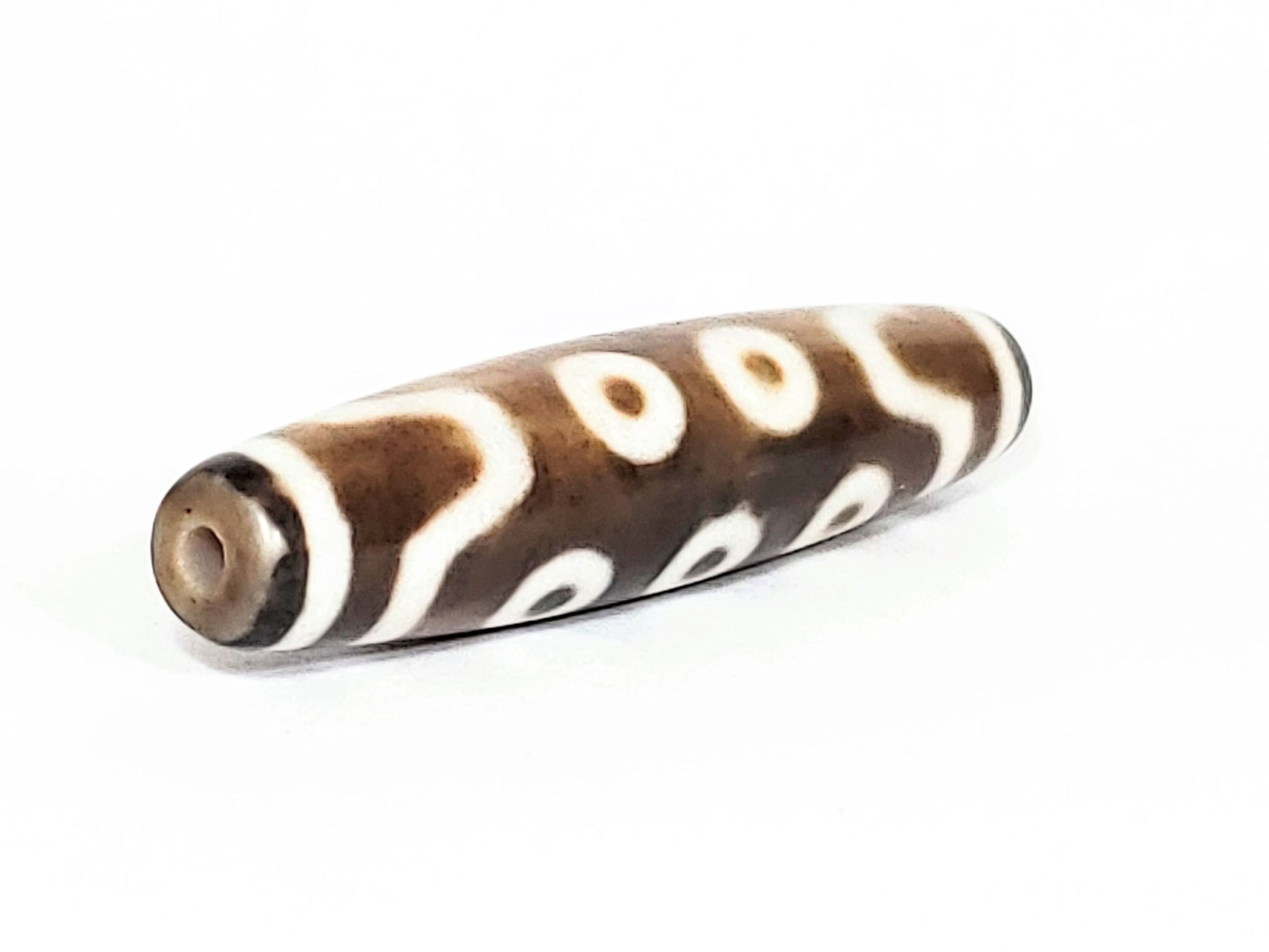 N-062426-10E new ten eye dzi 58.5x13.4mm angled view broader taper end drill hole warm brown agate unretouched