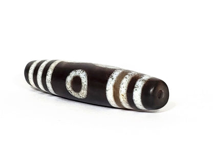 N-062426-3E new three eye dzi 58.6x13.4mm angled view end zone very deep dark brown near-black tip drill hole unretouched