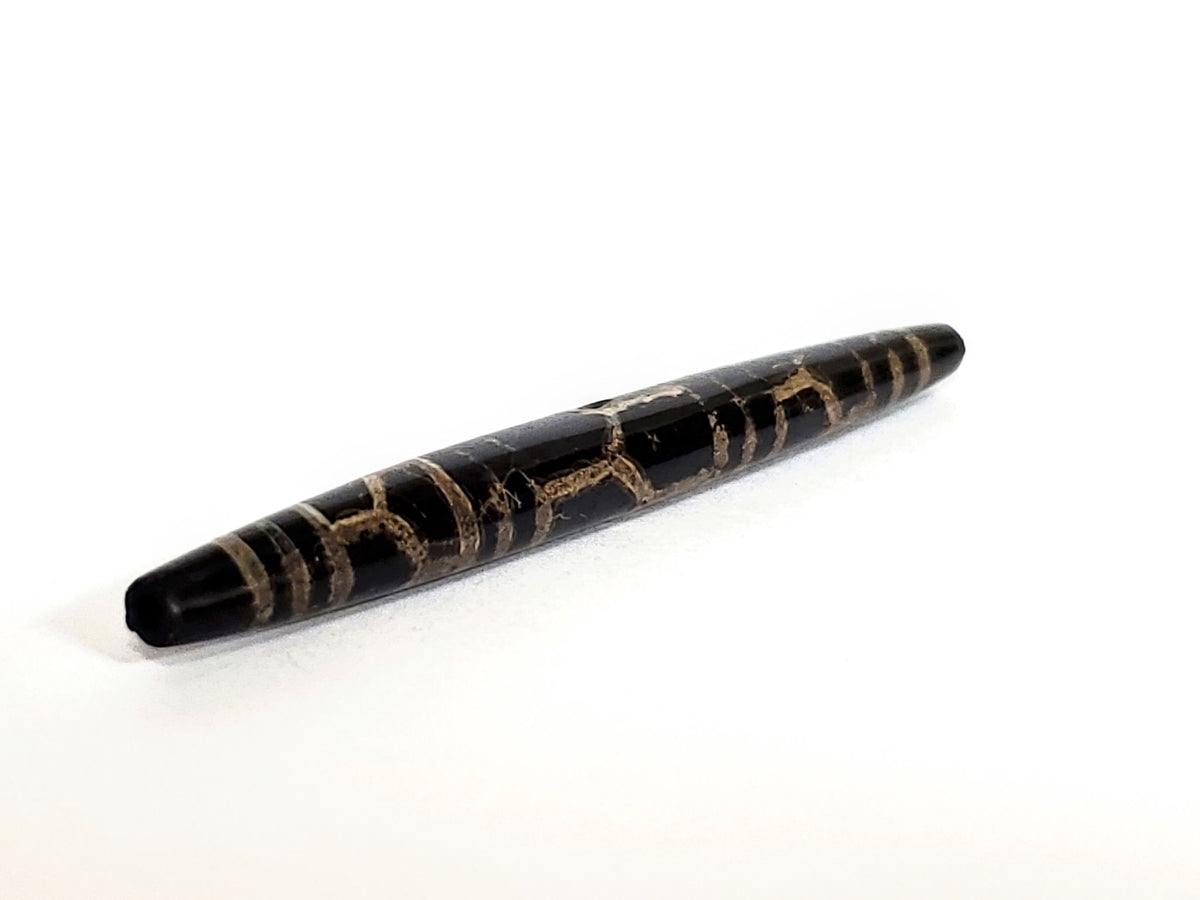 Ac-062926-3LG in display case, 75.3×8.2mm ancient triple longevity dzi, pitch-black agate warm-tan motif lines, unretouched