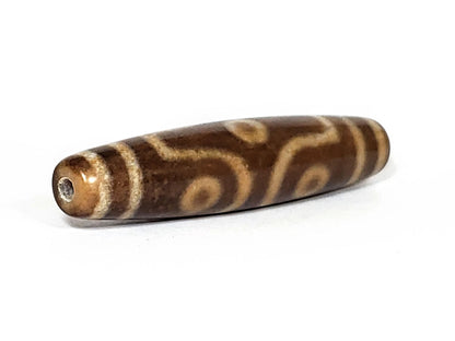 N-062226-6E2, angled toward broader end, drill hole centred, warm brown glossy end cap, motif visible, unretouched