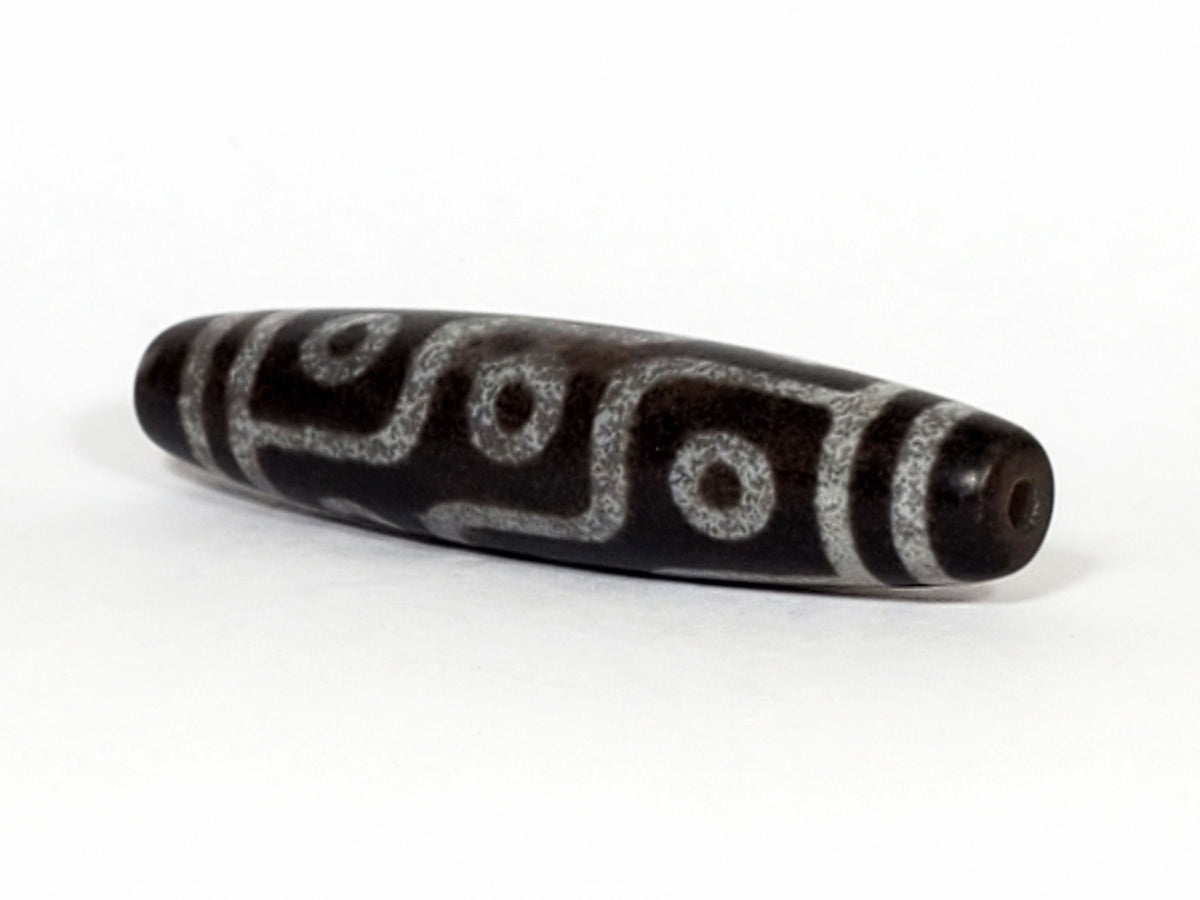 N-062226-9E3, angled view toward other end, drill hole centred, symmetric taper, warm brown matte ground, unretouched
