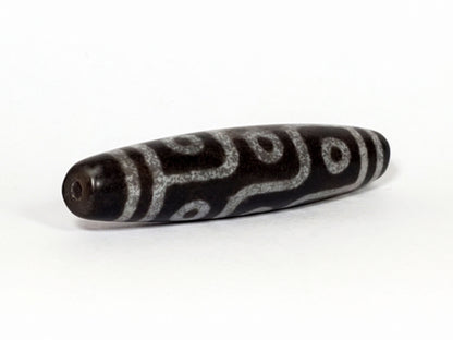 N-062226-9E, angled view toward broader end, drill hole centred, flowing curved motif visible, grey-black, unretouched