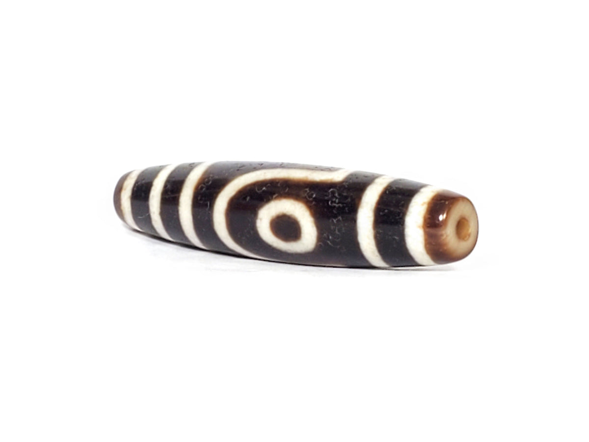 V-070426-2E3 dzi bead, diagonal view showing drill hole and eye motif, unretouched photo.