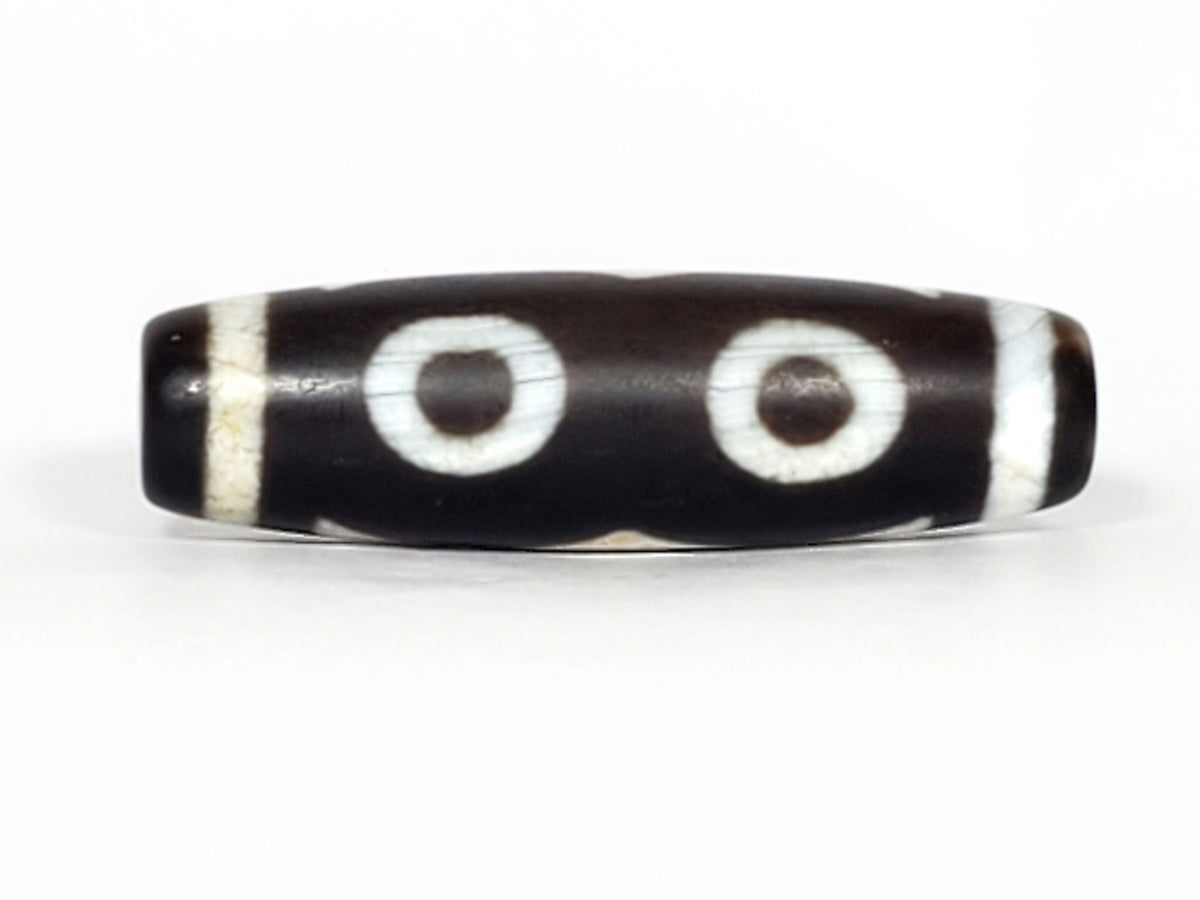 N-070226-3E dzi bead, diagonal view showing drill hole, black ground, unretouched photo.