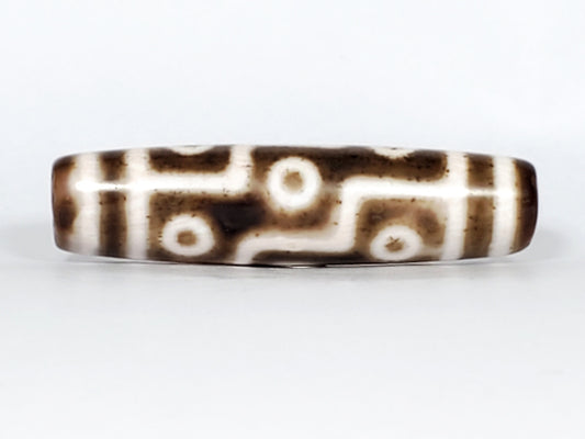 Antique nine-eye dzi bead, brown and white agate, eye motifs with circular rings, geometric lines, polished patina, Qing Dynasty