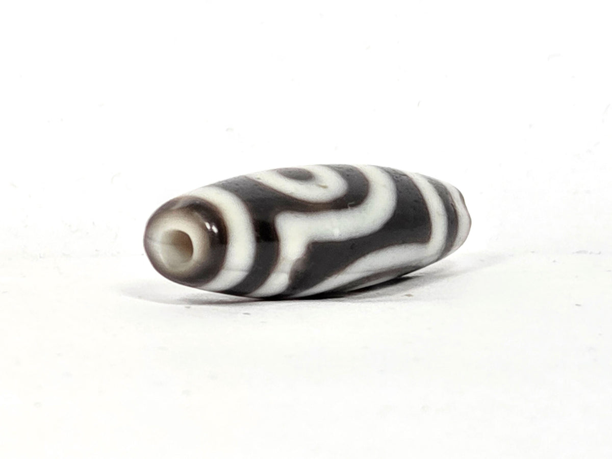 Opposite end cap of antique two eye dzi bead At-010726-2E3, dark brown agate tip with drill hole, second eye face partially visible, natural agate, unretouched