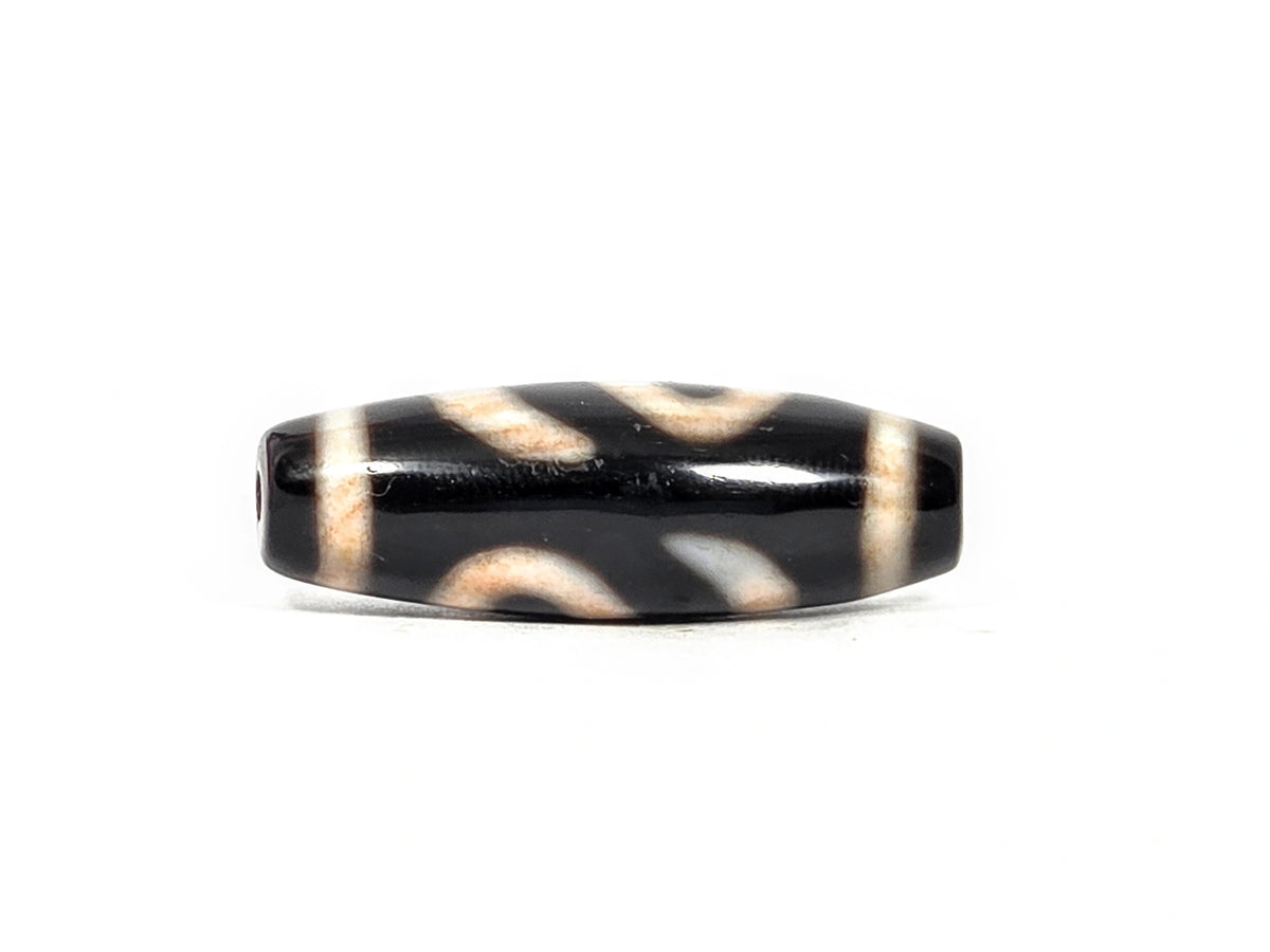 Second lateral profile of antique Tibetan money hook dzi bead showing reverse face with looping cream motif arcs and warm bloodspot amber tones in motif zones on pitch-black agate ground, 37.0 mm × 12.5 mm
