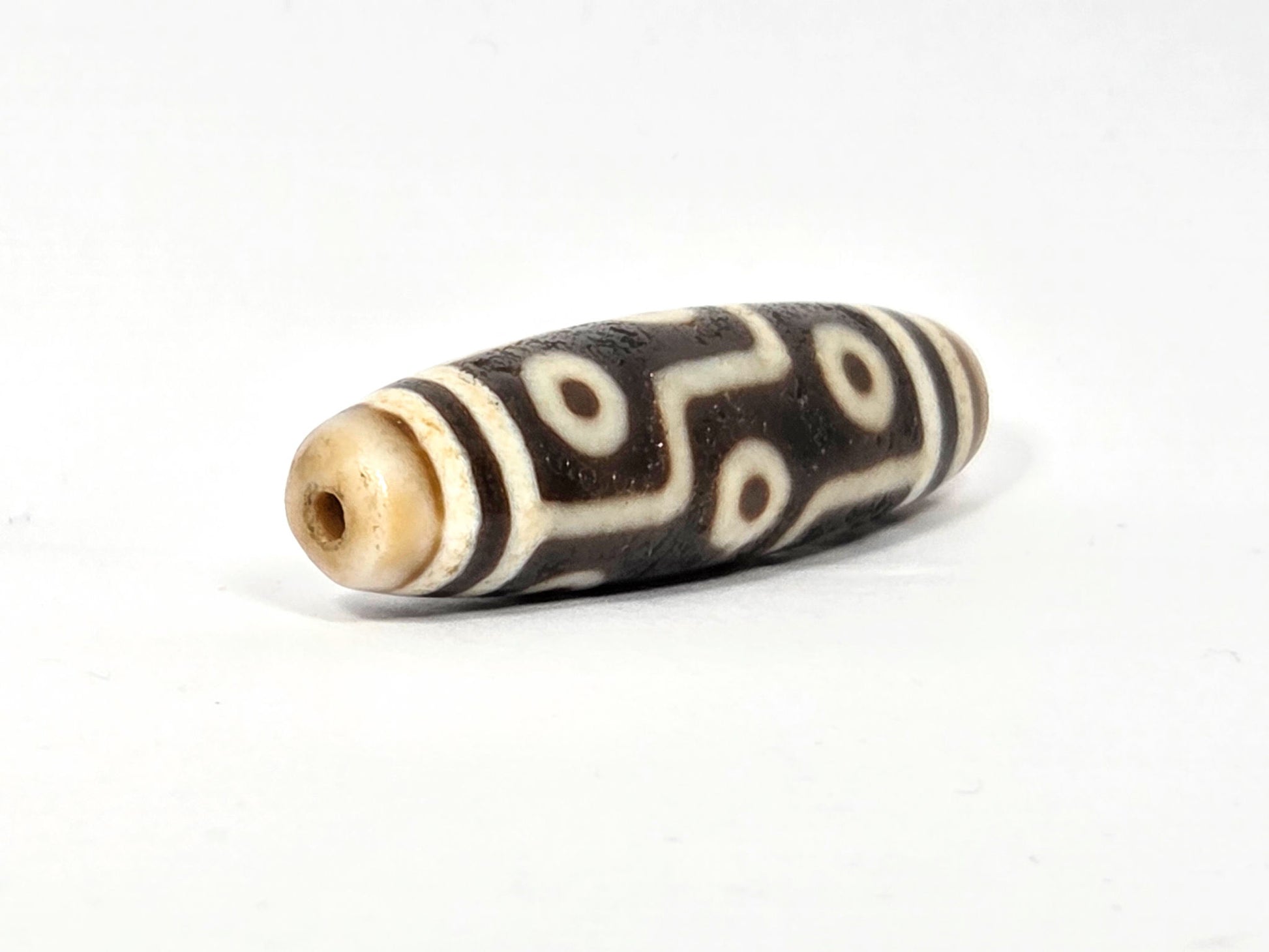 Angled view of ancient Nine Eye Dzi bead showing tapered profile and end — 54mm rare white agate, nine eye motif, ~800 years old