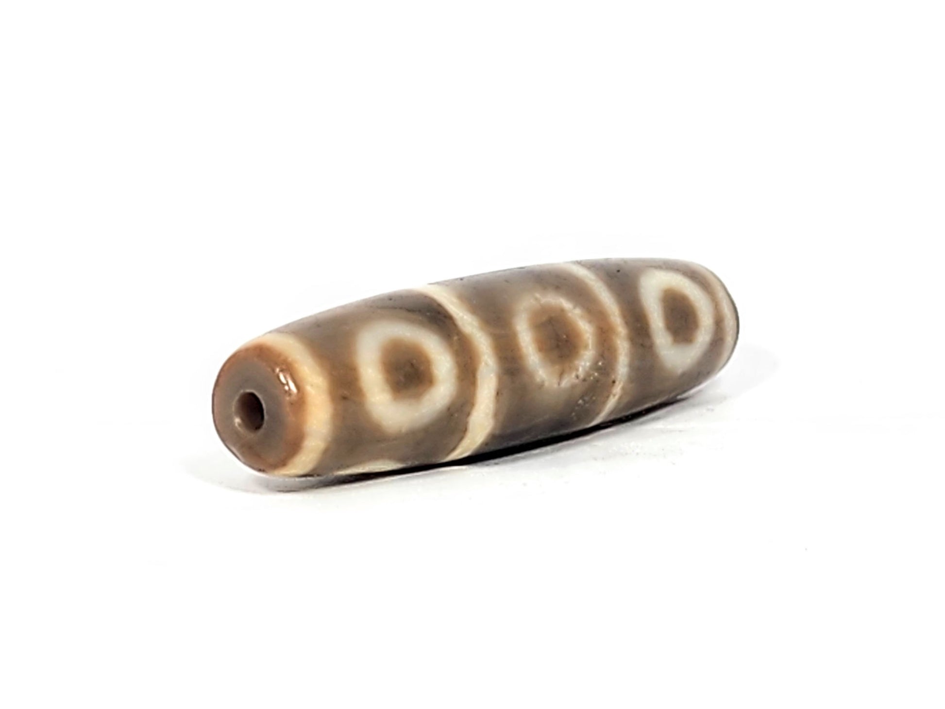Angled end of ancient Eight Eye Dzi — drill hole visible, slim taper, eye circles on upper face