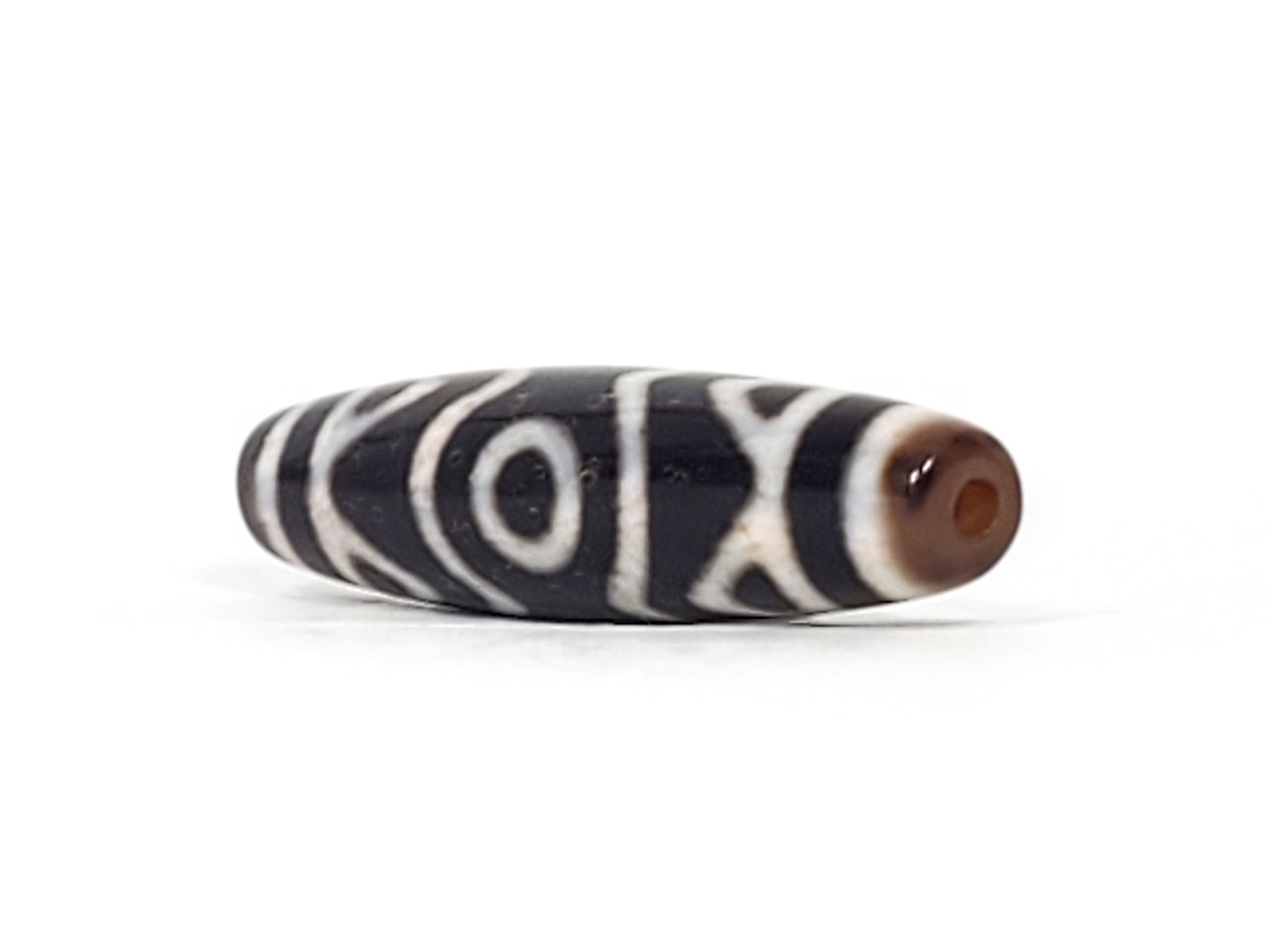 Ancient Three Eye Dzi bead showing deep red vermillion cinnabar bloodspot clearly visible at bead end, 500+ years old