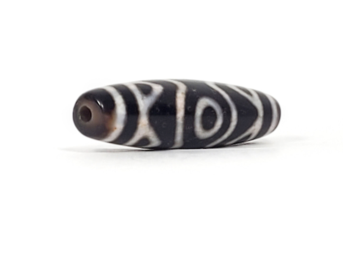 Fourth view of ancient Three Eye Tiger Tooth Dzi bead — large eye circle prominent, cinnabar bloodspot inclusion visible at bead end, natural agate