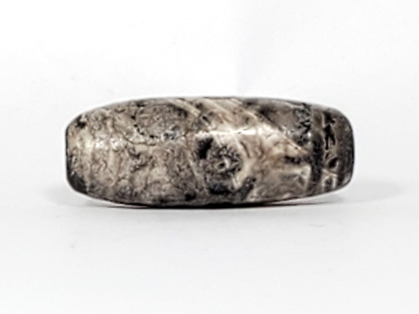 Third face of ancient Twelve Eye Lotus Dzi — lotus eye pattern visible under calcification