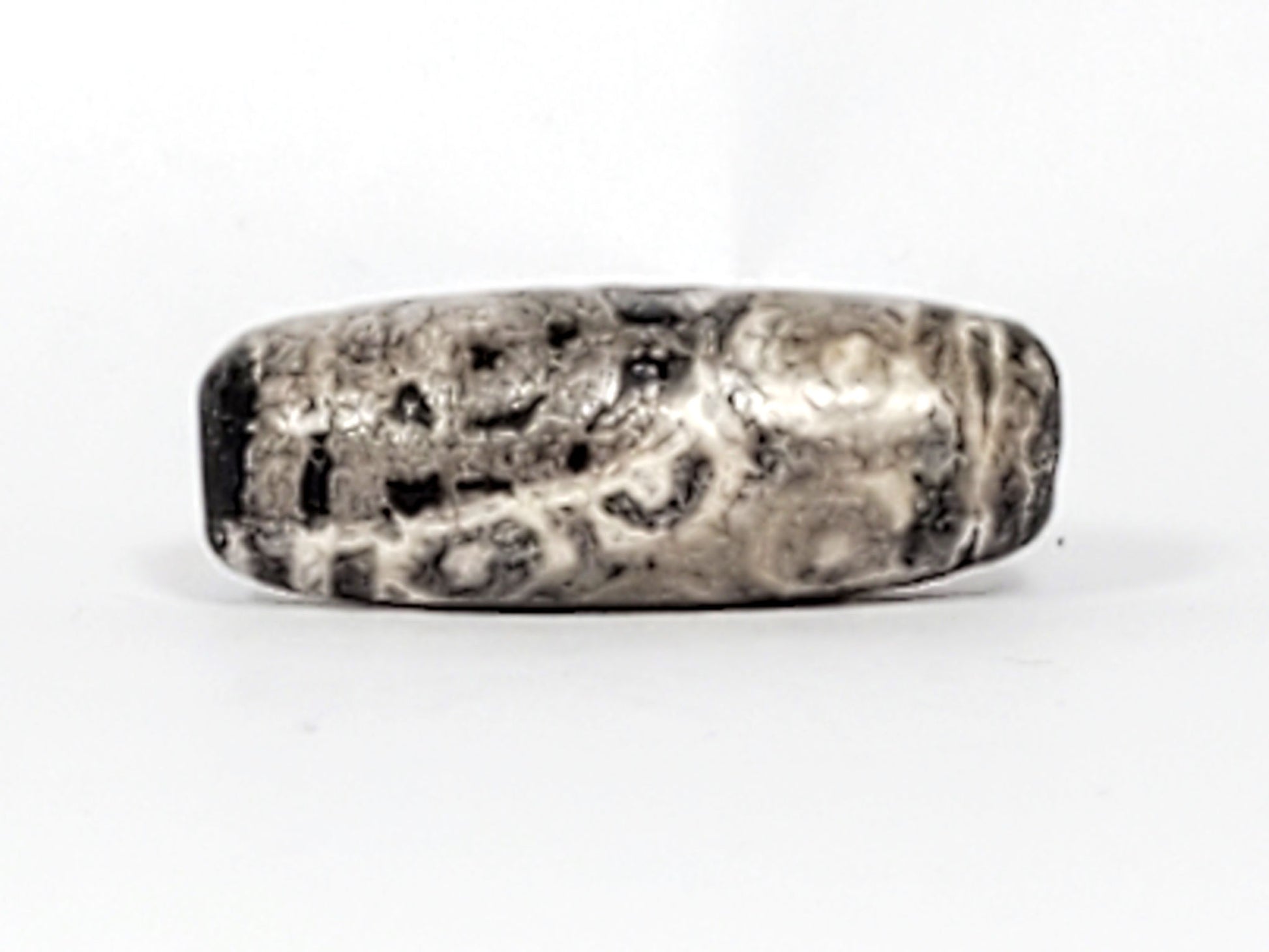 Fourth face of ancient Twelve Eye Lotus Dzi — eye circles most legible, cream and dark agate