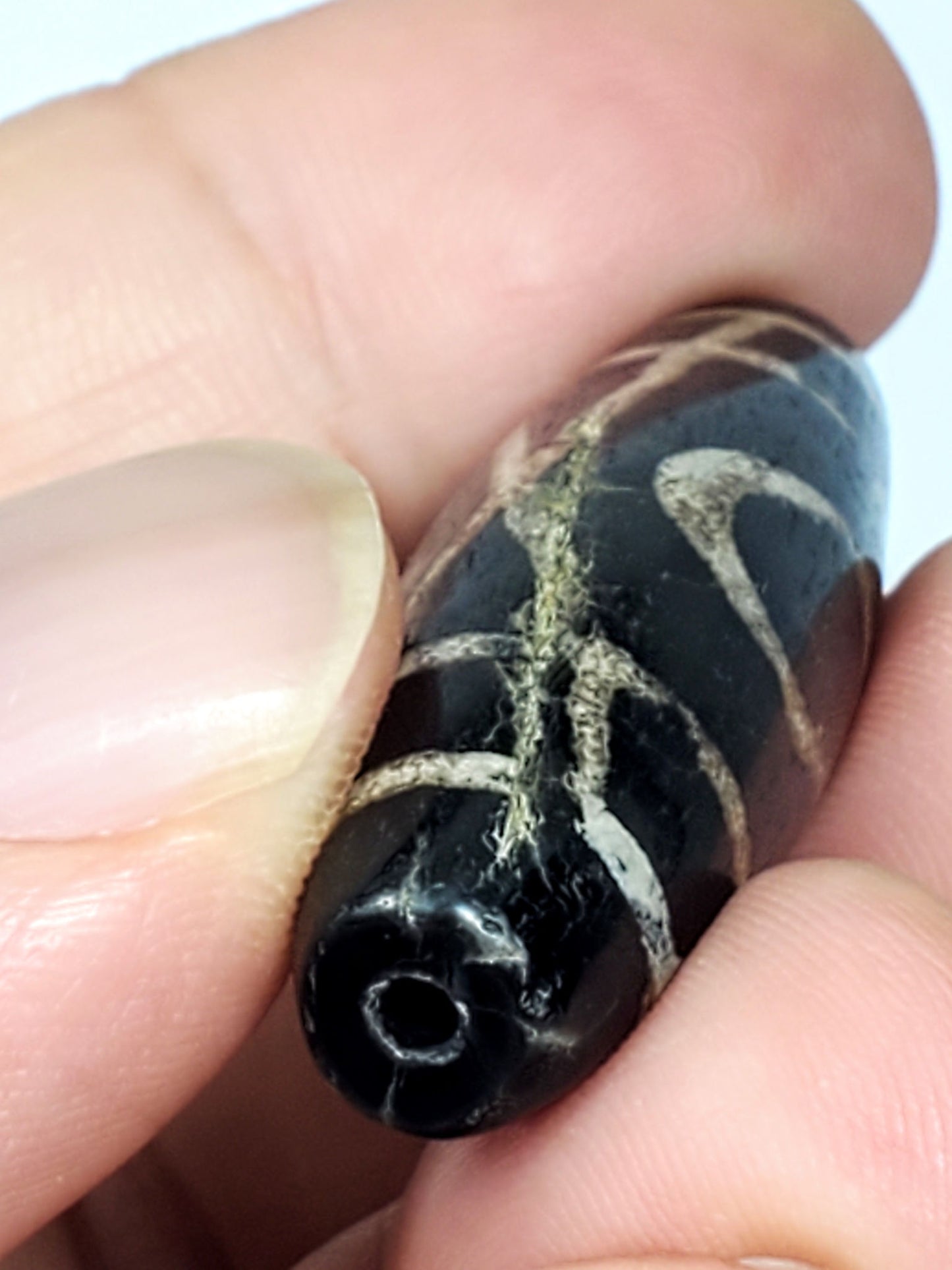 Close-up of Two Eye motif etched on ancient Tibetan Dzi bead — 1,500–2,000 years old, deep black natural agate