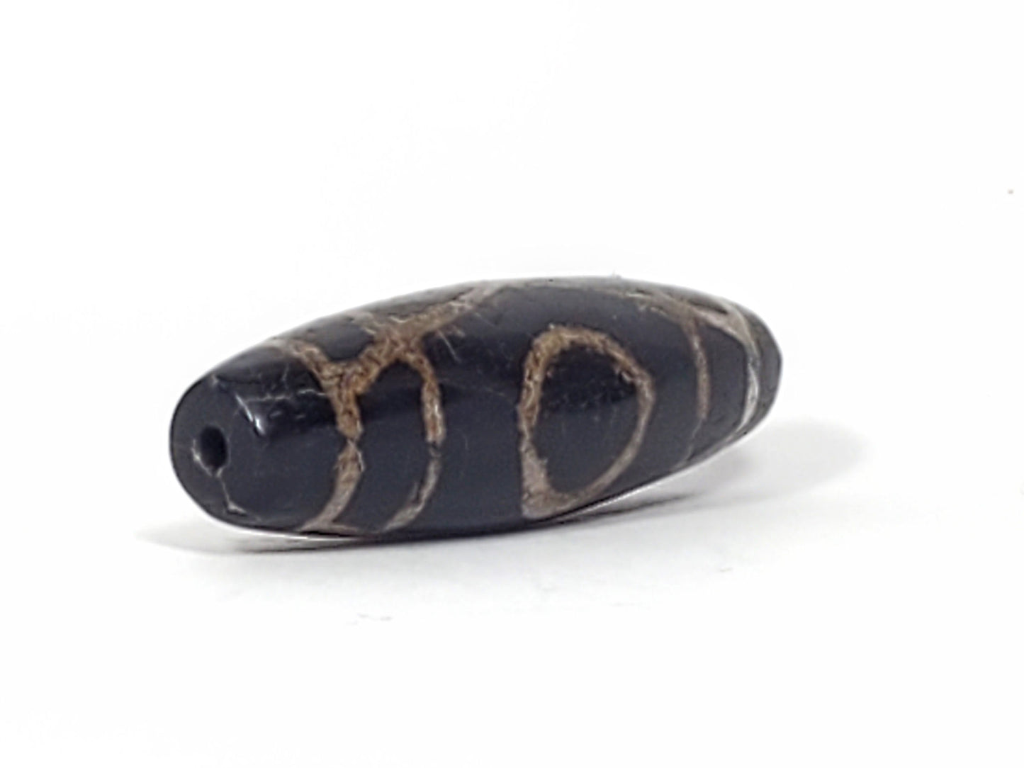 End view of ancient Two Eye Dzi bead showing drill hole and natural agate banding — 1,500–2,000 years old, unretouched