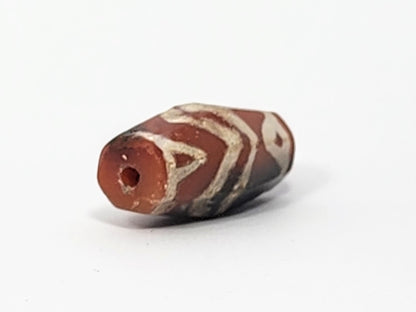 Ac-061126-TSTT angled end, small drill hole, vivid orange-red end cap against grey-black body, motif visible, unretouched