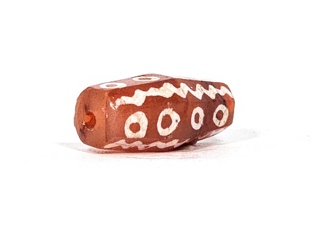 Ac-010825-16EW angled end, drill hole, octagonal facets visible, 4 ring eyes, wave band, terracotta-red, unretouched