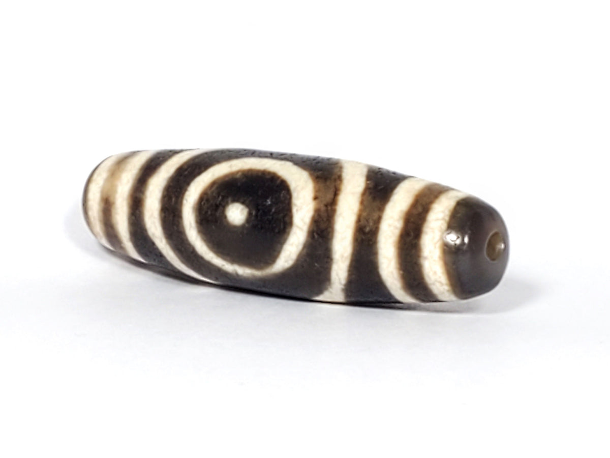 Ac-082325-DHE2 opposite end angled, drill hole left, sandy-brown tip, oval and stripe motif wrapping body, unretouched