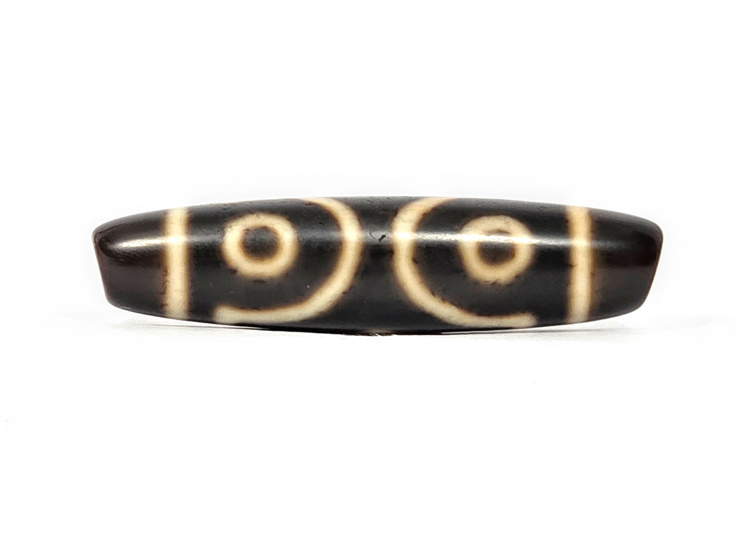 Opposite side of ancient Tibetan Three Eye Dzi bead — cream eye motif etching visible on dark natural agate, 500+ years old