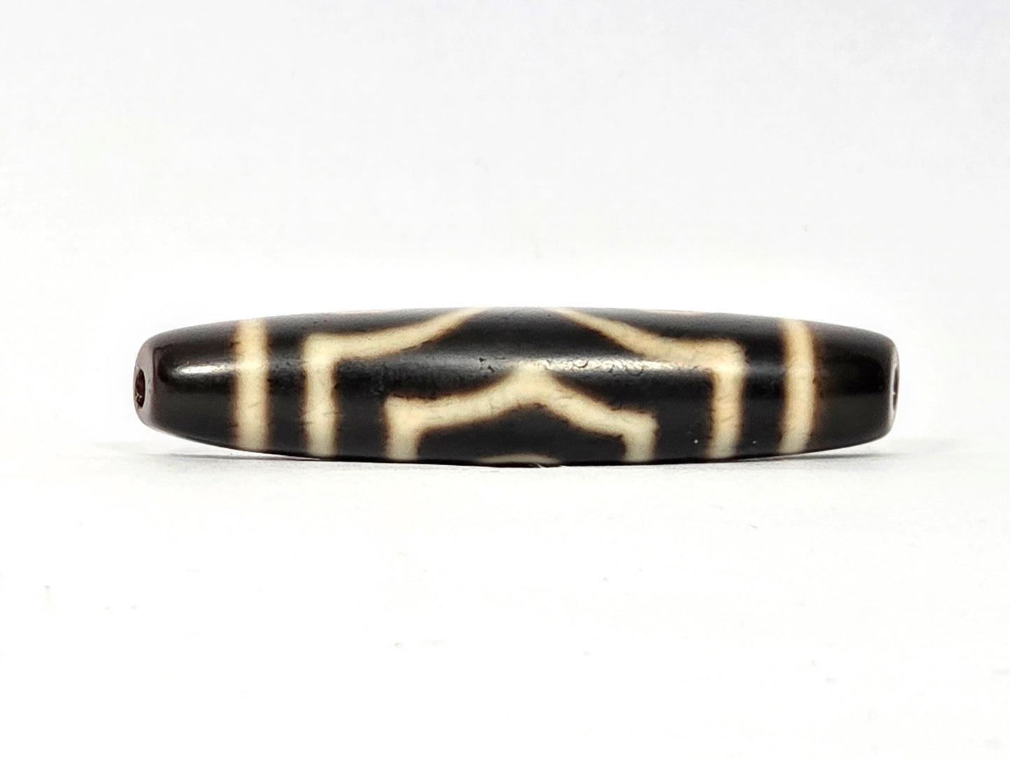 Three-quarter angled view of ancient Three Eye Dzi bead — 51.5mm natural agate showing depth of etched eye circles