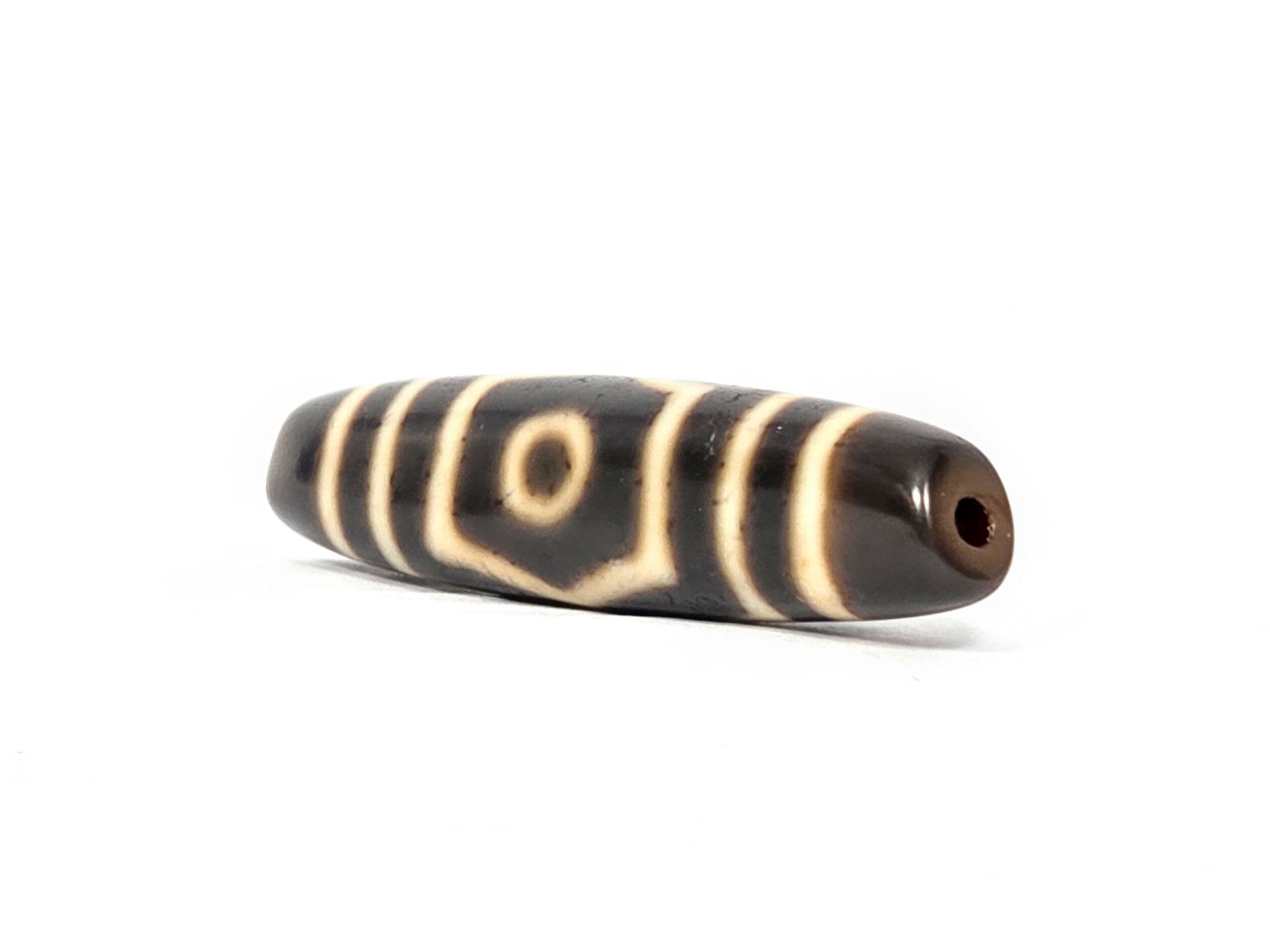 End view of ancient Tibetan Three Eye Dzi bead showing drill hole and natural agate banding — unretouched photograph