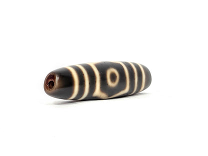End view of ancient Tibetan Three Eye Dzi bead showing drill hole and natural agate banding — unretouched photograph