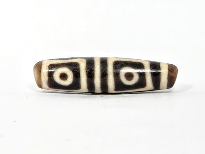 Four-eye dzi bead, square-framed eye motifs, deep warm brown agate, cream stripes, smooth patina, 49.5mm elongated barrel shape