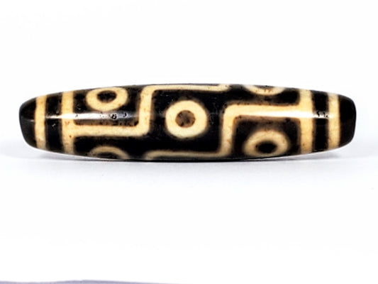 Ancient Tibetan nine-eye dzi bead, black and cream agate, geometric eye motifs, natural patina, elongated barrel shape