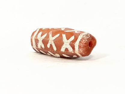 Ac-062426-12X ancient twelve X-cross carnelian dzi 28.5x11.0mm angled view drill hole end orange-red tip unretouched