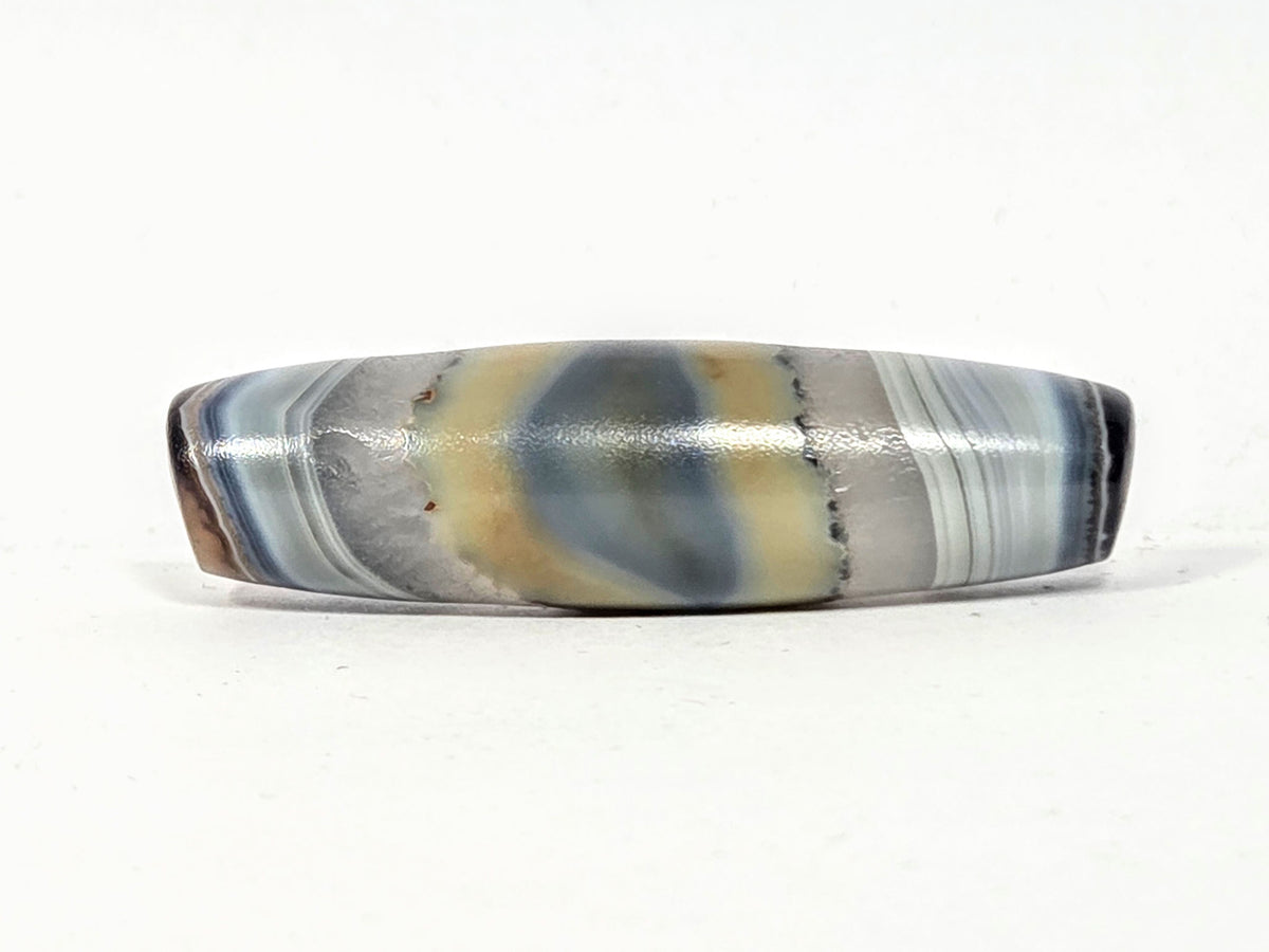Antique one-eye dzi bead, banded grey-blue agate, natural eye motif, cream patina, polished surface, elongated barrel shape