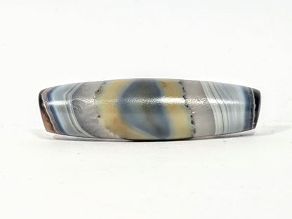 Antique one-eye dzi bead, banded grey-blue agate, natural eye motif, cream patina, polished surface, elongated barrel shape