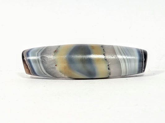 Antique one-eye dzi bead, banded grey-blue agate, natural eye motif, cream patina, polished surface, elongated barrel shape