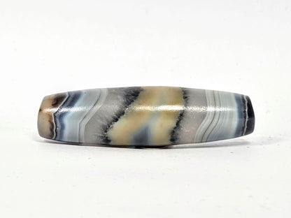 Antique one-eye dzi bead, natural agate, grey black cream banding, wave patterns, polished surface, aged patina, elongated barrel shape