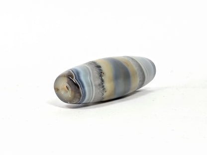 Antique one-eye Dzi bead, striped grey-blue agate, natural patina, visible drill hole, earthy tan banding, matte surface texture