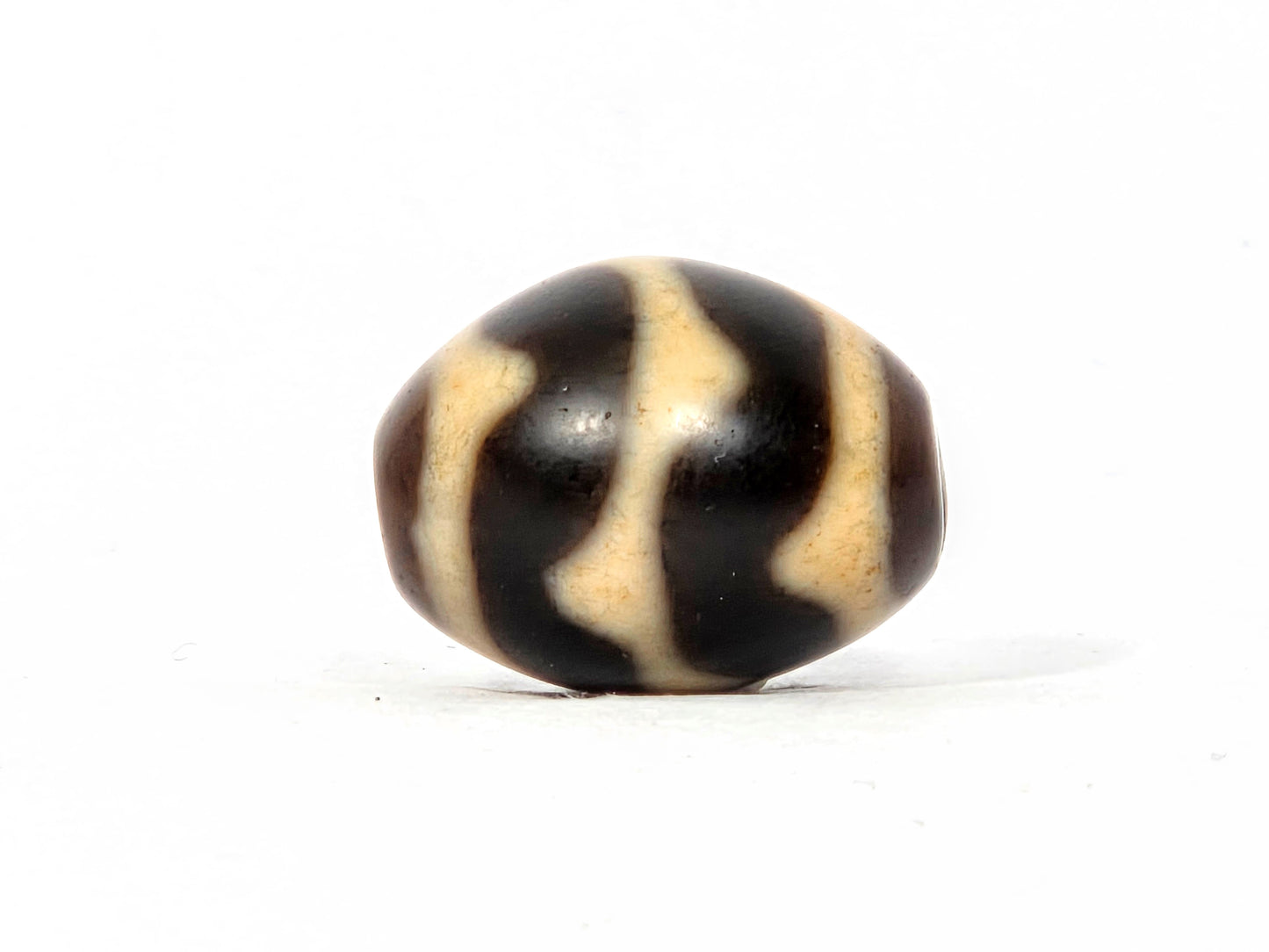 Black and beige striped bead on a white background