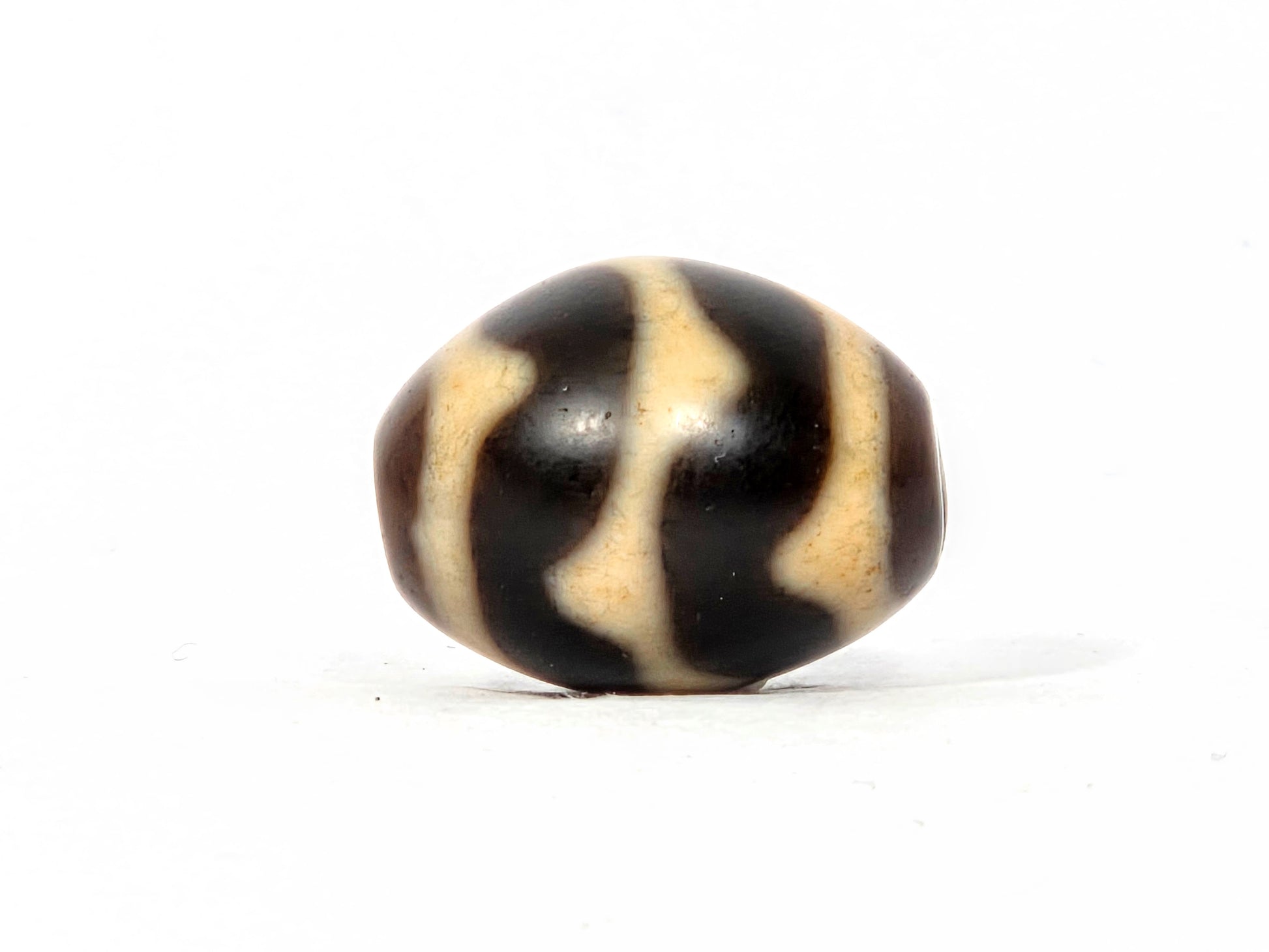 Black and beige striped bead on a white background