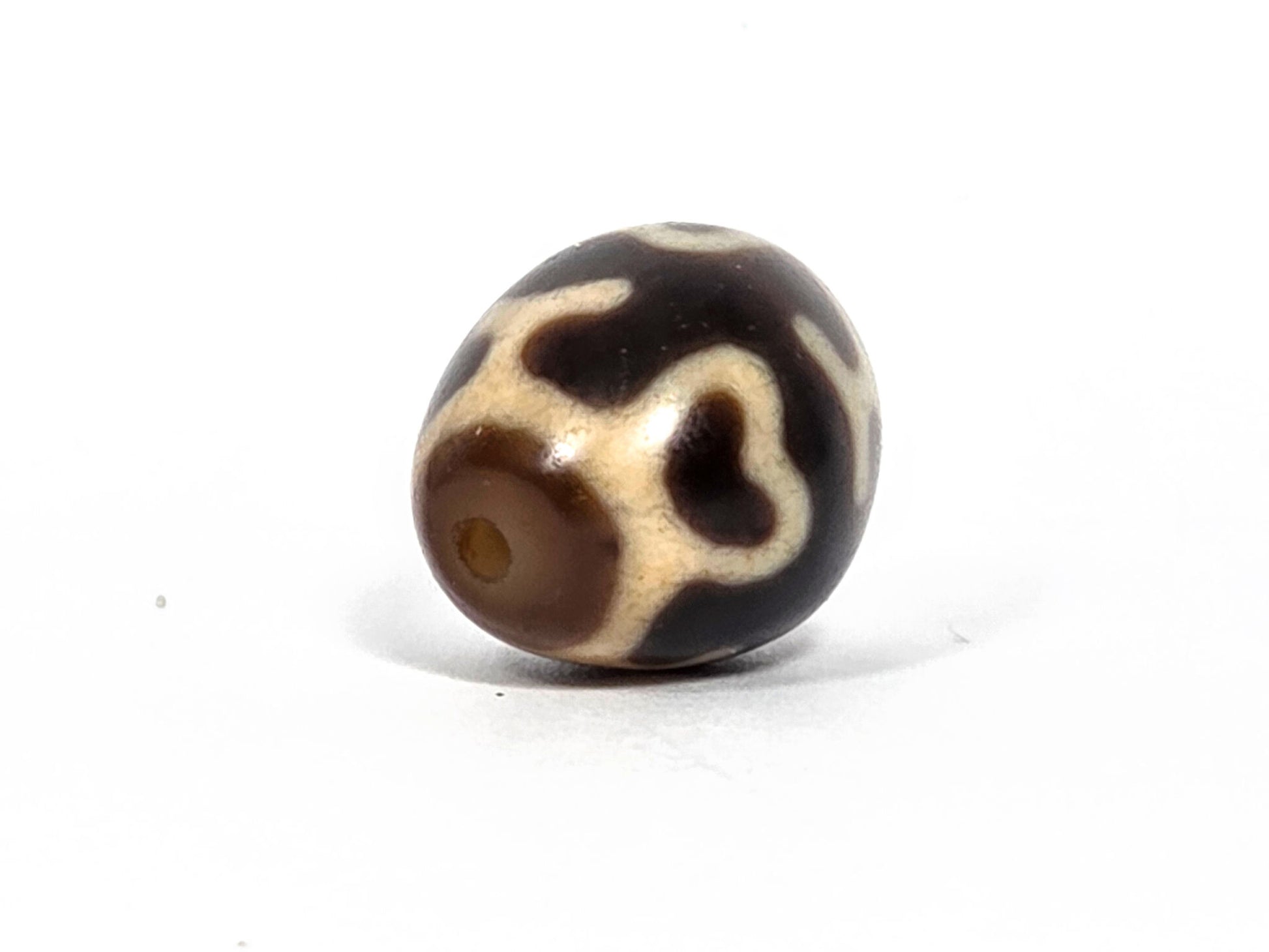 At-080926-4ELT antique round dzi bead 19.9×16.6mm, rotation F showing cream heart-lotus form and drill hole at lower left, unretouched
