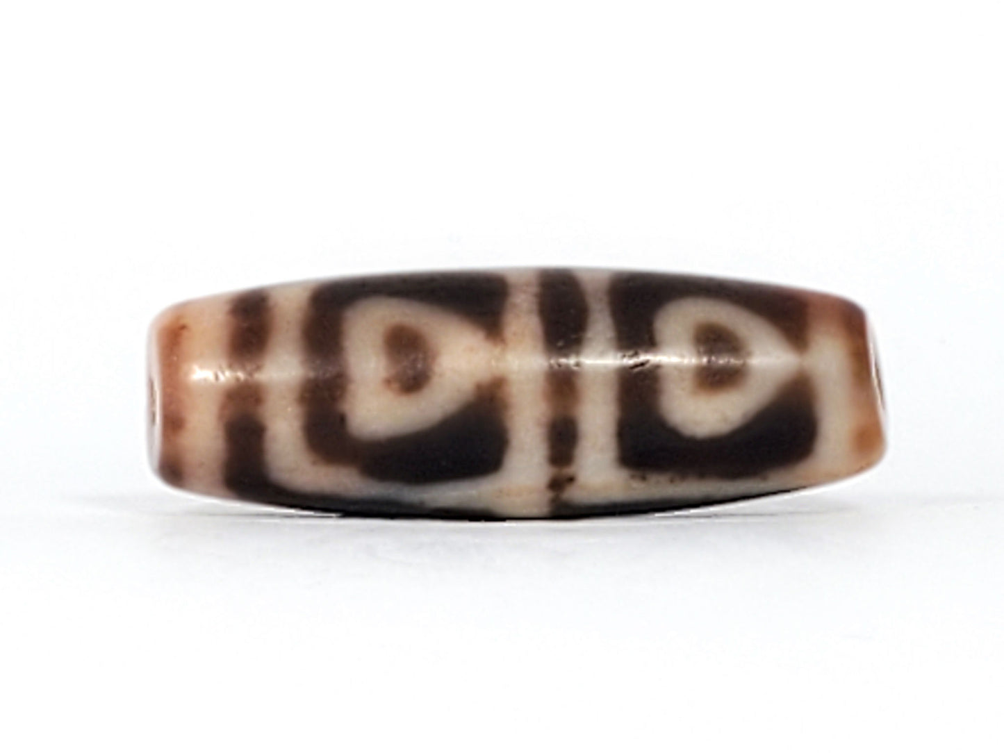 Antique Tibetan Four Leaf Bodhi dzi bead At-101624-FLB, front face showing four arch-leaf motifs in cream on amber-brown agate, bloodspots visible, 35.7mm × 12.1mm, unretouched