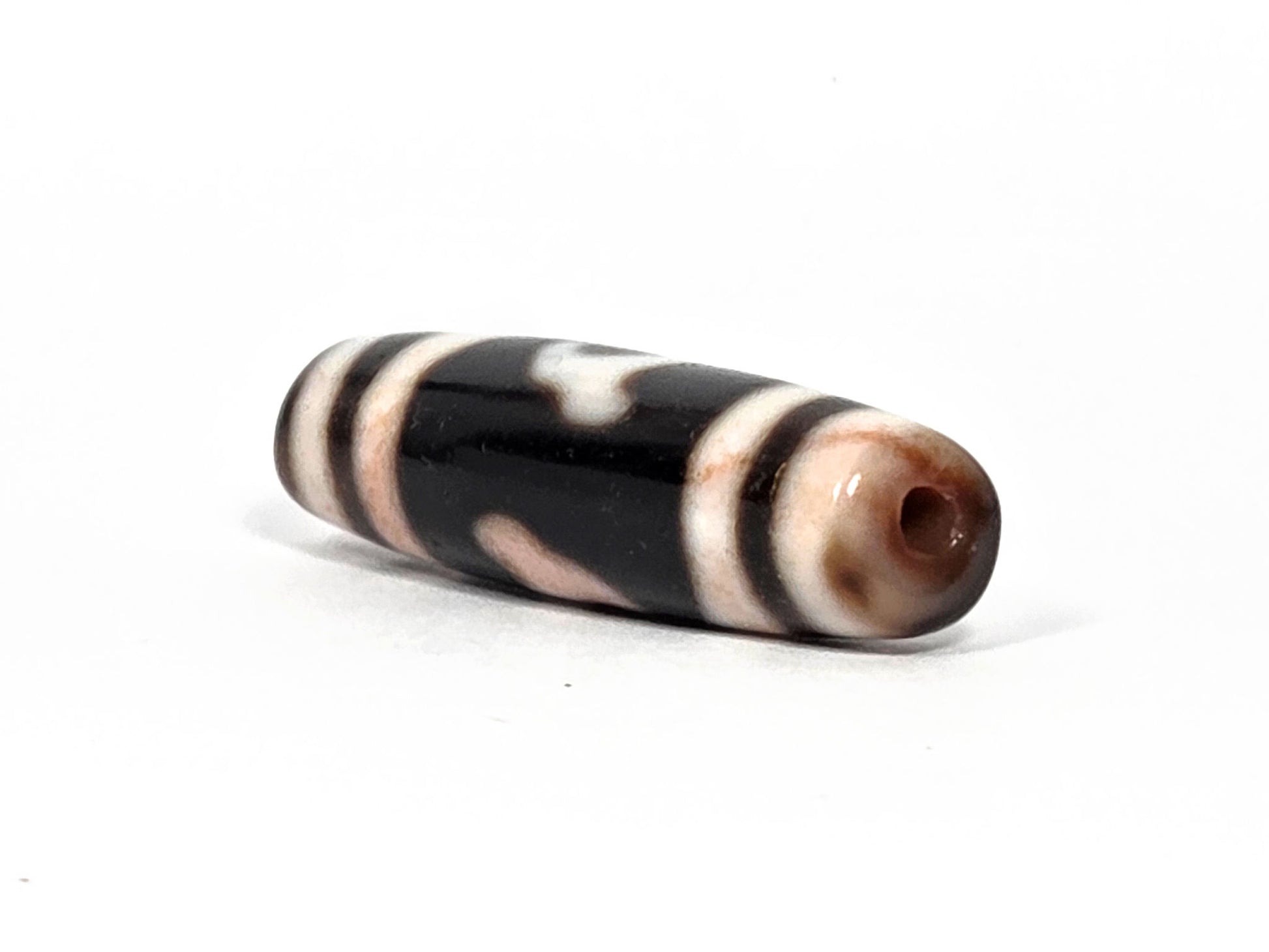 At-080426-GTBS antique Green Tara dzi bead 37.9×11.0mm, angled drill-end view showing warm brown agate end cap and straight-sided profile, unretouched