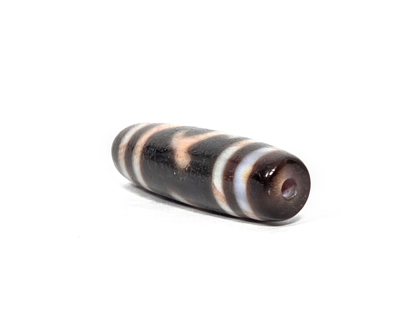 At-080426-GTBS2 antique Green Tara dzi bead 37.8×10.8mm, angled drill-end view showing warm dark brown agate end cap and fusiform taper, unretouched
