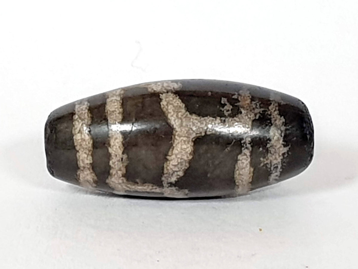 Antique Tibetan dzi bead longevity motif, dark brown agate, white etched pattern, aged patina, oval barrel shape