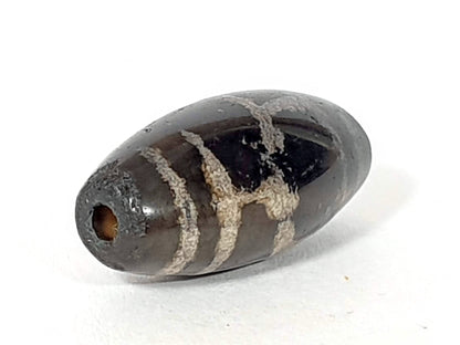 Antique longevity motif dzi bead, dark agate, white etched lines, visible drill hole, aged patina, oval barrel shape