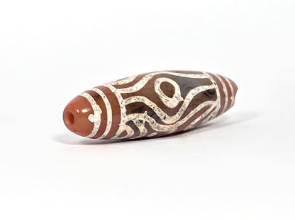 At-061426-2ETTSt carnelian dzi, RIGHT END CHIP DISCLOSED — concave impact chip at tip, drill hole intact, unretouched