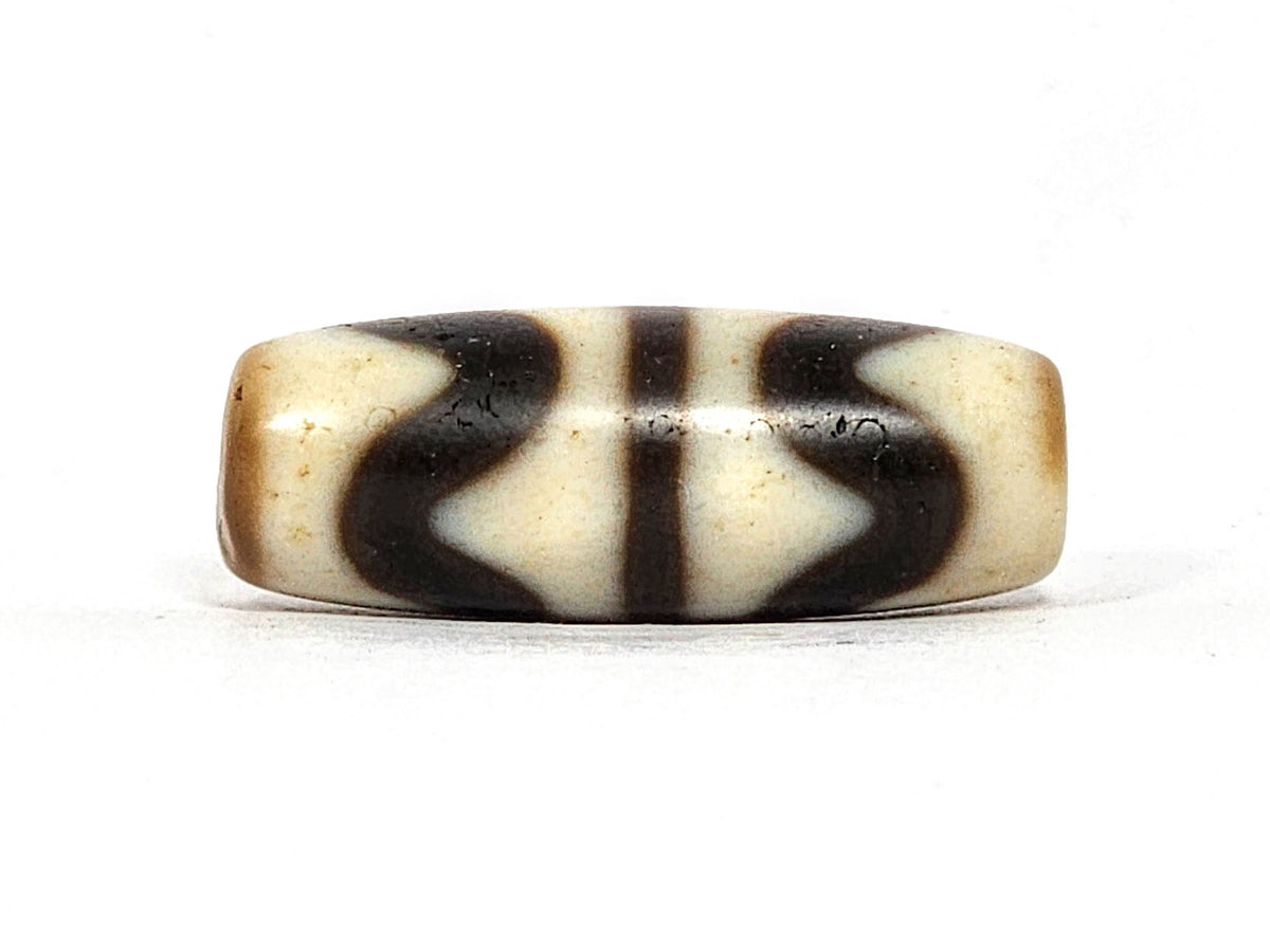 Second face of antique Double Wave dzi At-072325-DW5, cream double wave motif on warm brown agate, compact barrel form, flanking vertical stripes visible, 28.4mm, unretouched