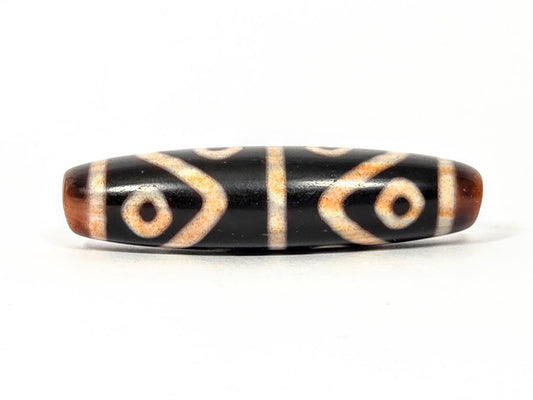 Fourth face of antique Eight Eye Tiger Tooth Dzi — eye circles, tiger tooth forms, warm brown ends