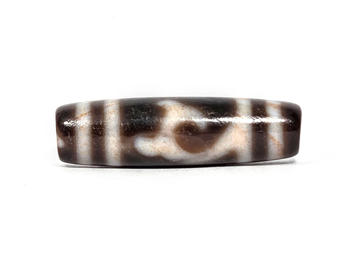 At-080426-GTBS2 antique Green Tara dzi bead 37.8×10.8mm, Face A showing scroll motif on very dark brown ground, cream lines with peach bloodspot tinge, unretouched