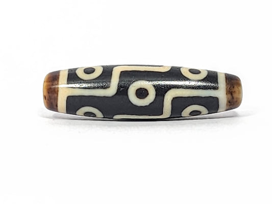 Antique Tibetan nine-eye dzi bead, black agate with cream eye motifs and maze lines, brown patina at drill holes