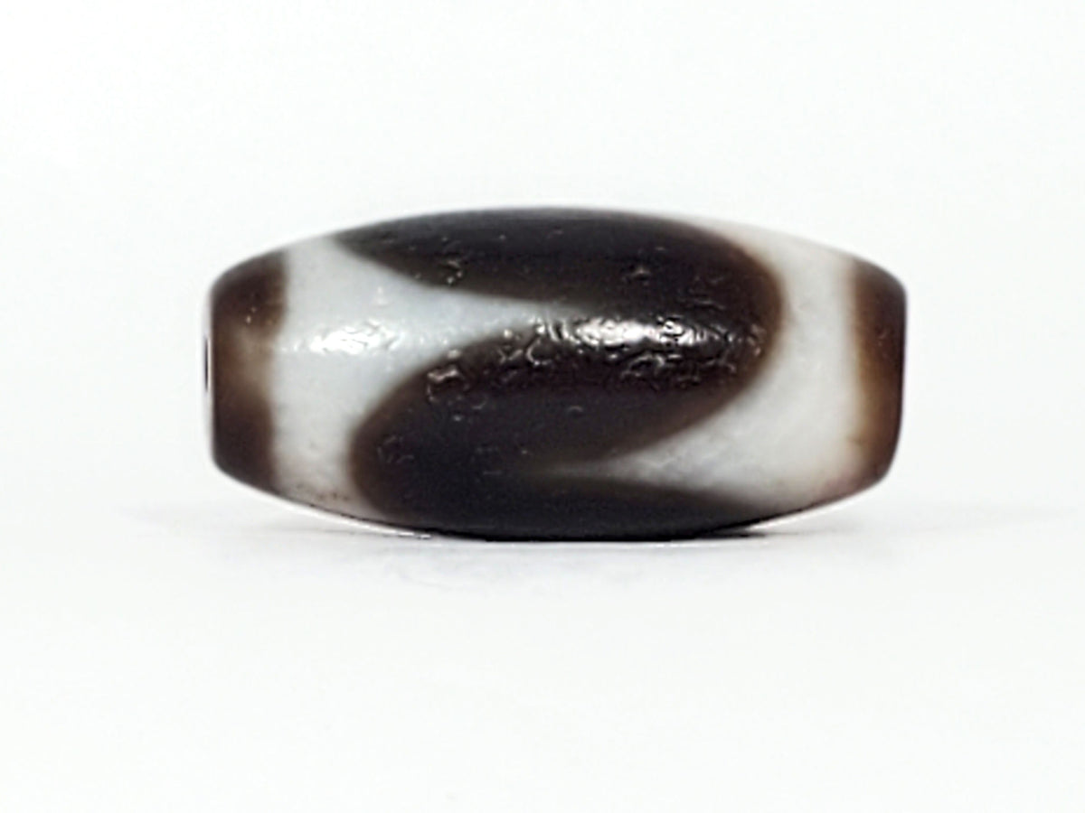 Third face of antique Tasso dzi At-093024-TaBS3, sweeping cream wave motif on chocolate-brown agate, bloodspot cinnabar inclusions visible, wide disc-like barrel form, unretouched